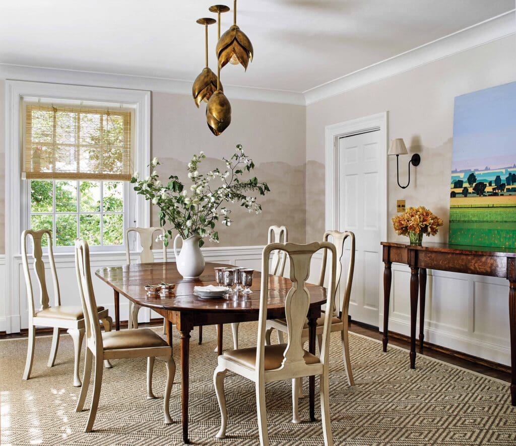The dining room features wallpaper from Schumacher, Chik blinds from Evans & Sheldon, and a modern pendant cluster from Arteriors. The Sarah Gayle Carter painting was sourced through Palette Home in Richmond. The dining table is from Helen Storey in Charlottesville. The chairs were in the client’s childhood home, and Anne Pulliam had Holtz & Son refinish and reupholster them in Moore & Giles leather. 
